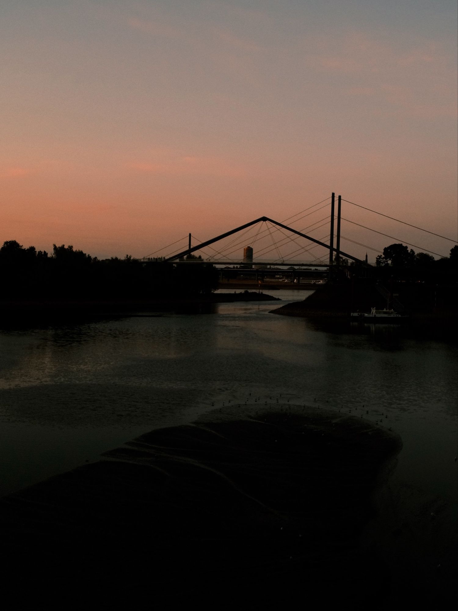 Silhouette of a Rhine bridge over the water at dusk in Düsseldorf