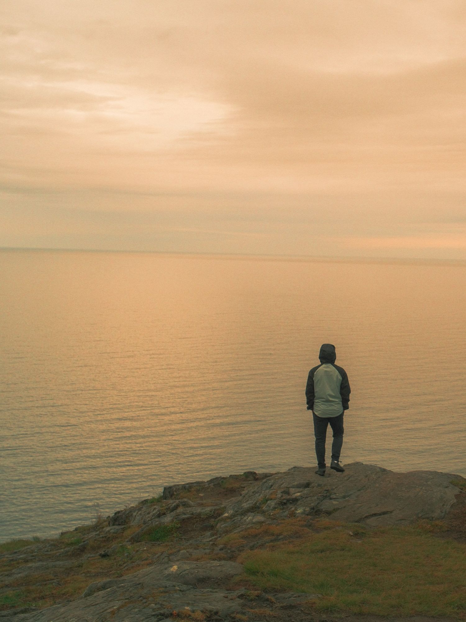 Hiker standing on a rock above a hazy fjord on Senja, Norway