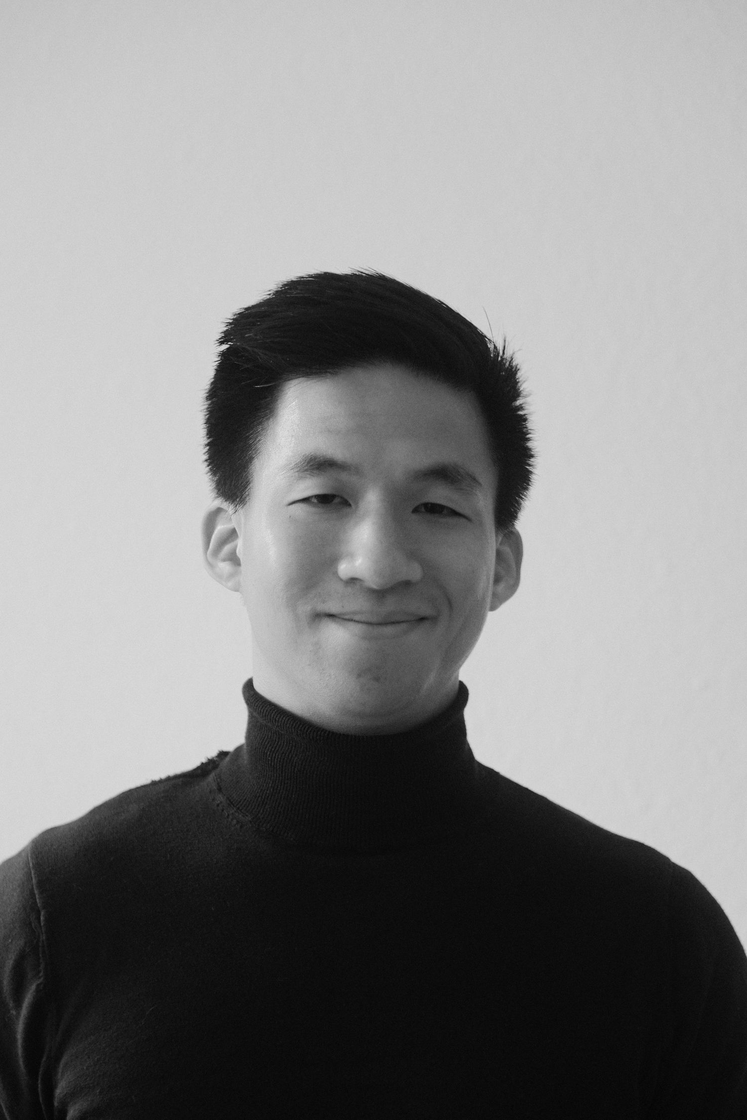 Black and white portrait of travel photographer Dinh Huy in a black turtleneck