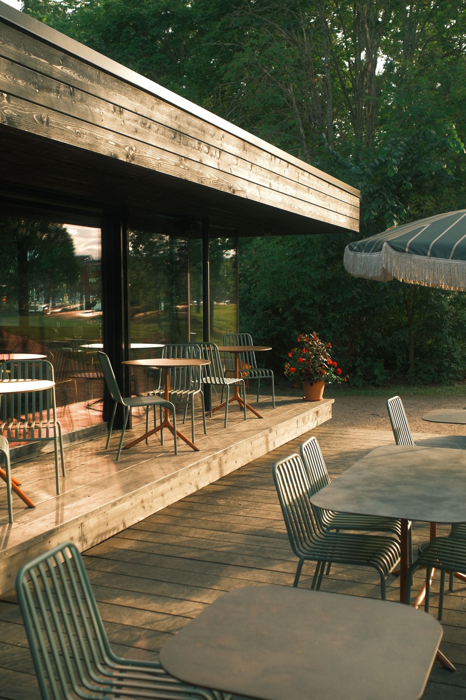 Sunlit wooden terrace of a lakeside café with empty chairs