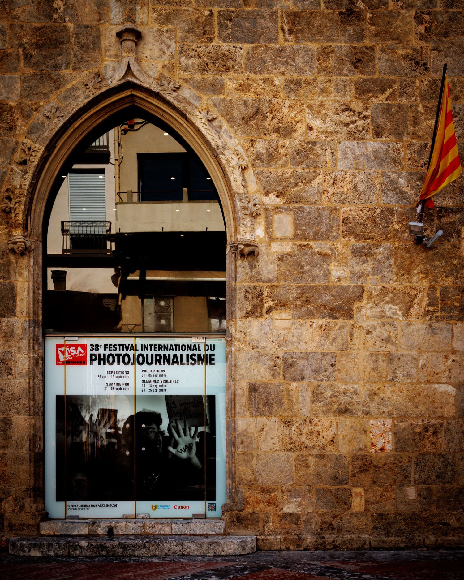 Visa Pour L'Image international photojournalism festival poster in Gothic stone archway door.