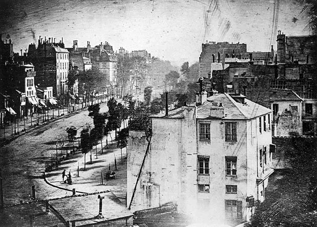 Historic daguerreotype of a Parisian boulevard in 1838, showing early street photography with buildings and tree-lined avenue.