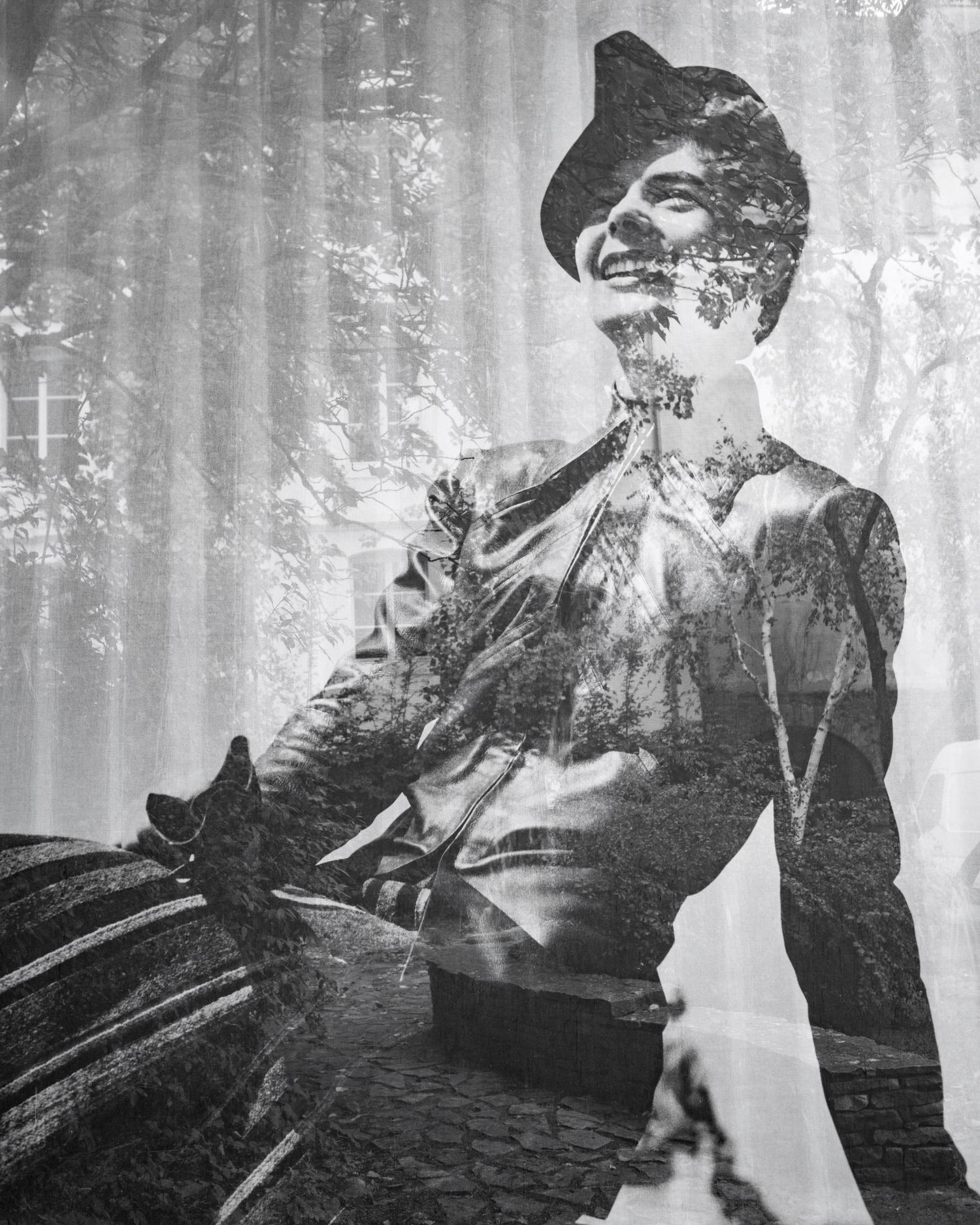 Black and white double exposure photo of a smiling woman in vintage attire overlaid with forest trees.