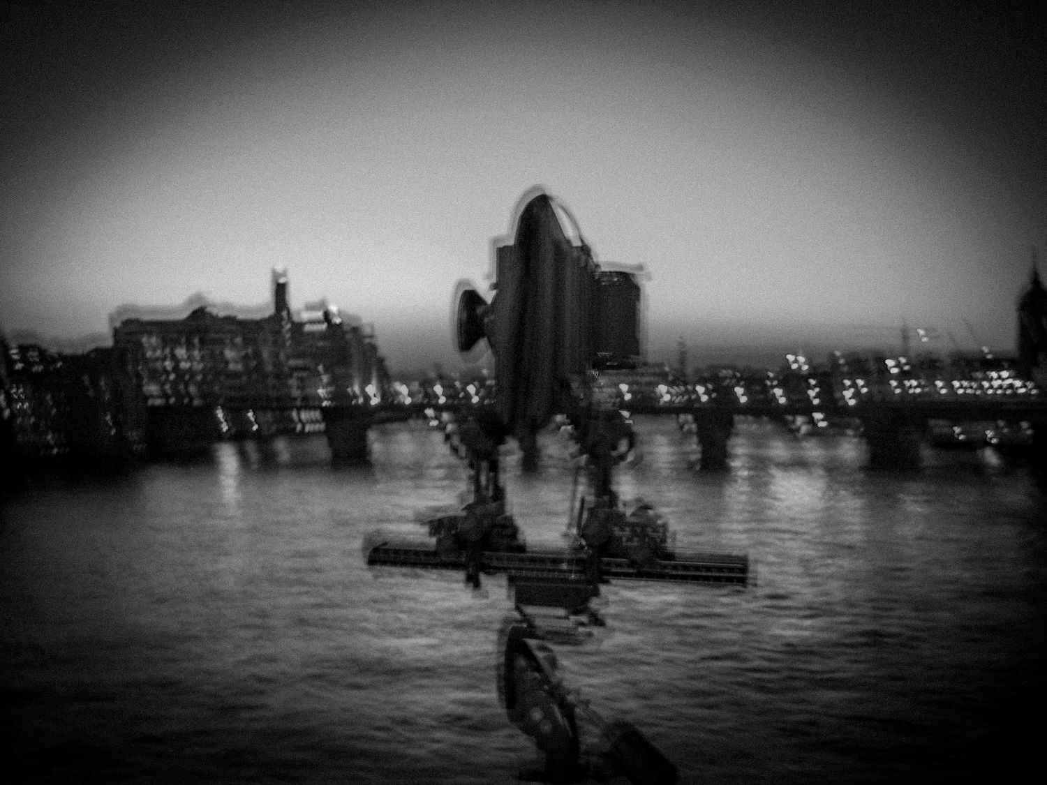 Surreal black and white reflection of city skyline in dark water.
