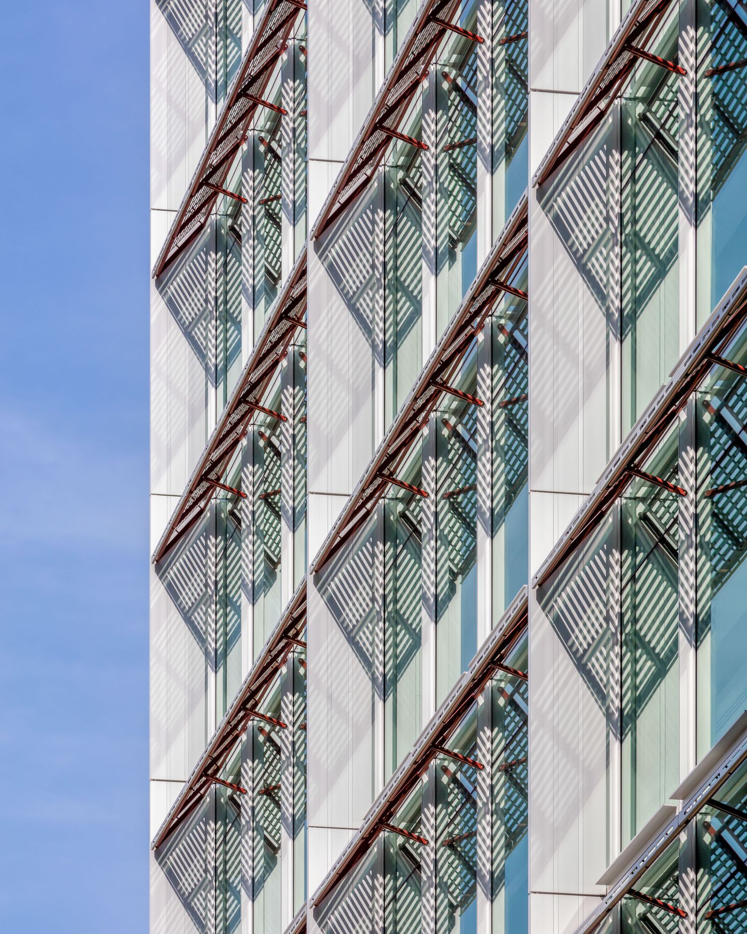 Close-up architectural detail of a modern building facade featuring decorative diamond-patterned metal screens and glass panels.