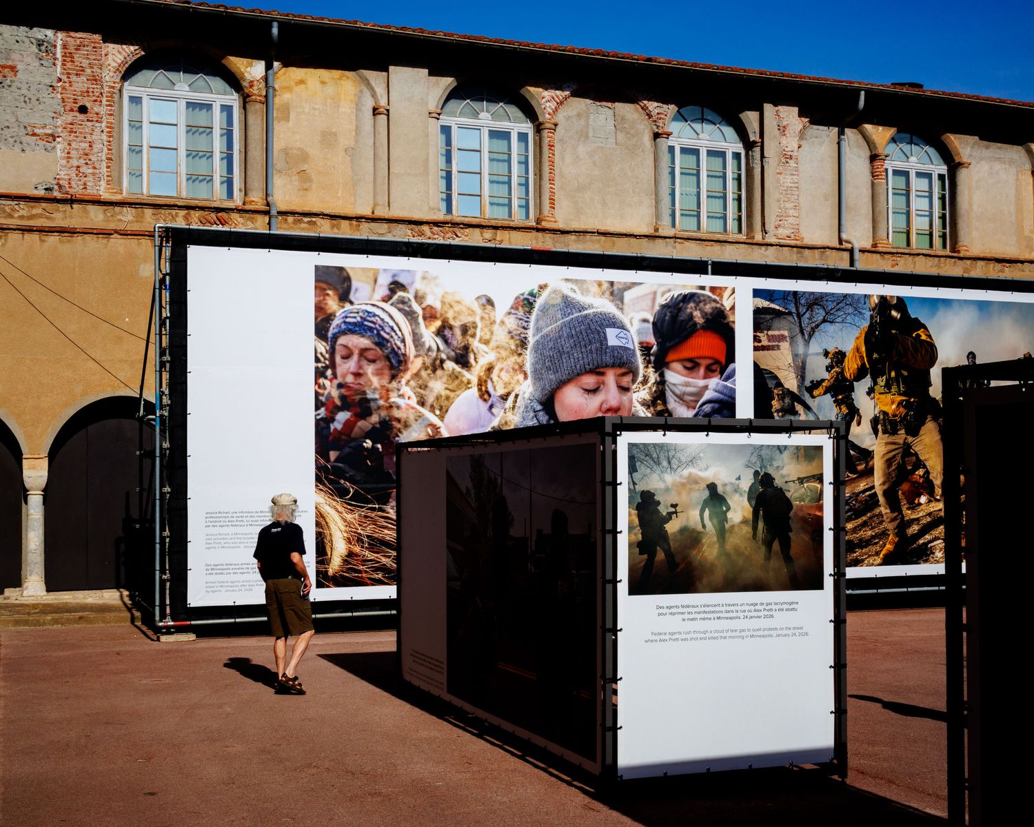 Outdoor photojournalism exhibition displays large format prints on panels outside a historic building.