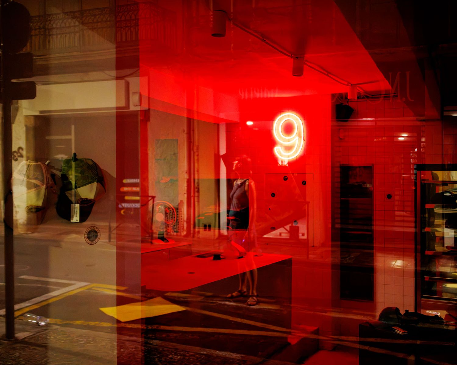 Red neon number 9 sign glowing in a shop window with colorful reflections at night.