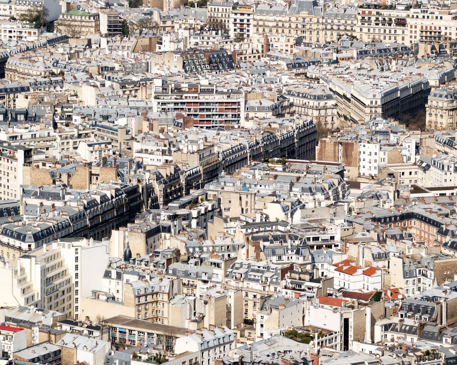 High aerial view of dense Parisian rooftops and Haussmann buildings stretching across the city.