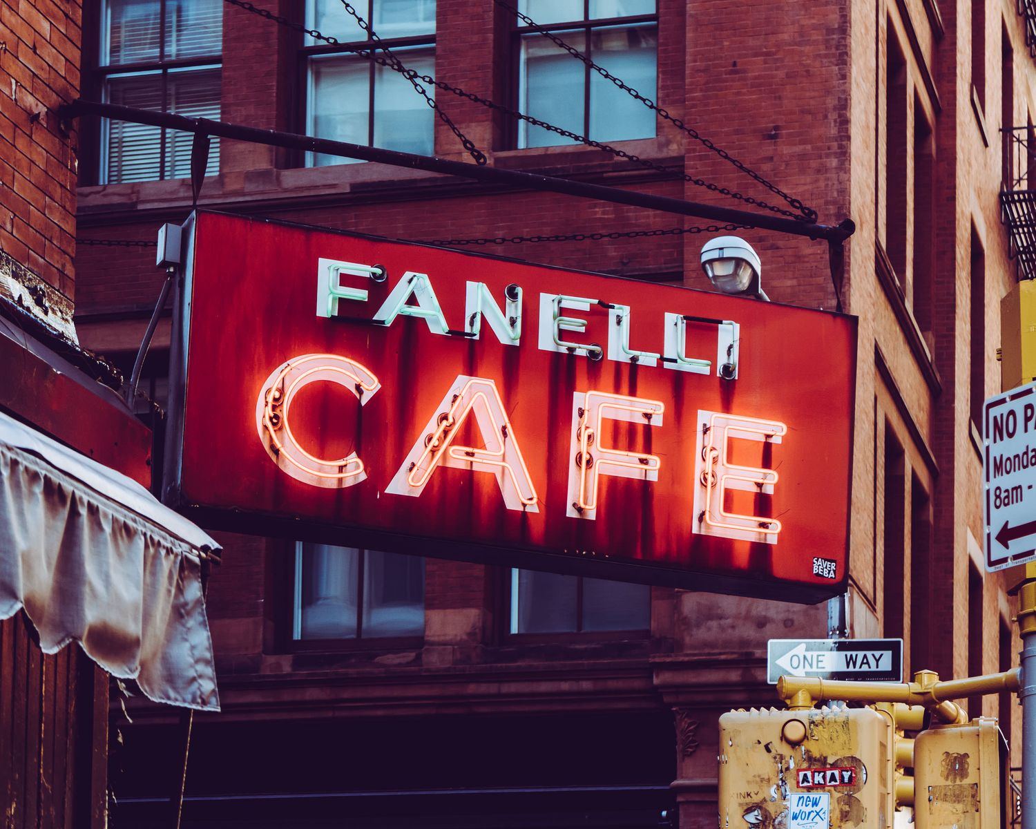 Fanelli Cafe neon sign glowing red on a brick building corner in New York City.