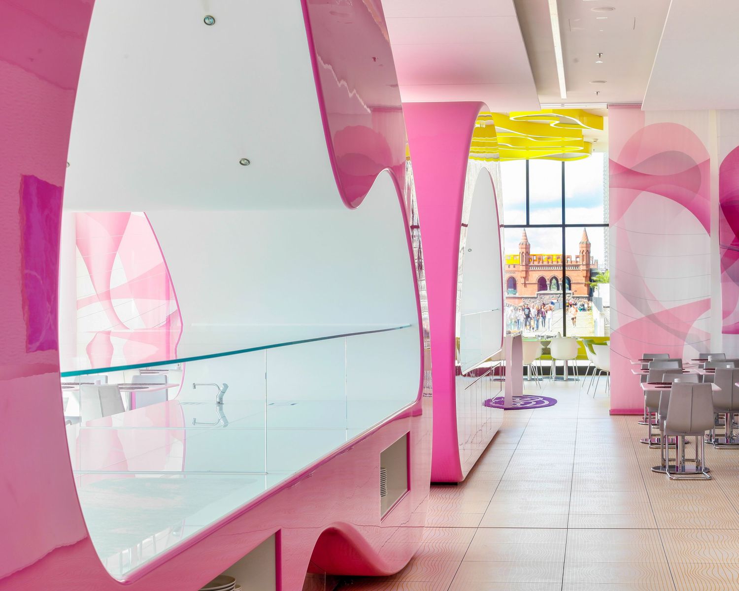 Vibrant pink and yellow modern interior design of a stylish restaurant with futuristic curved walls and sleek furniture.