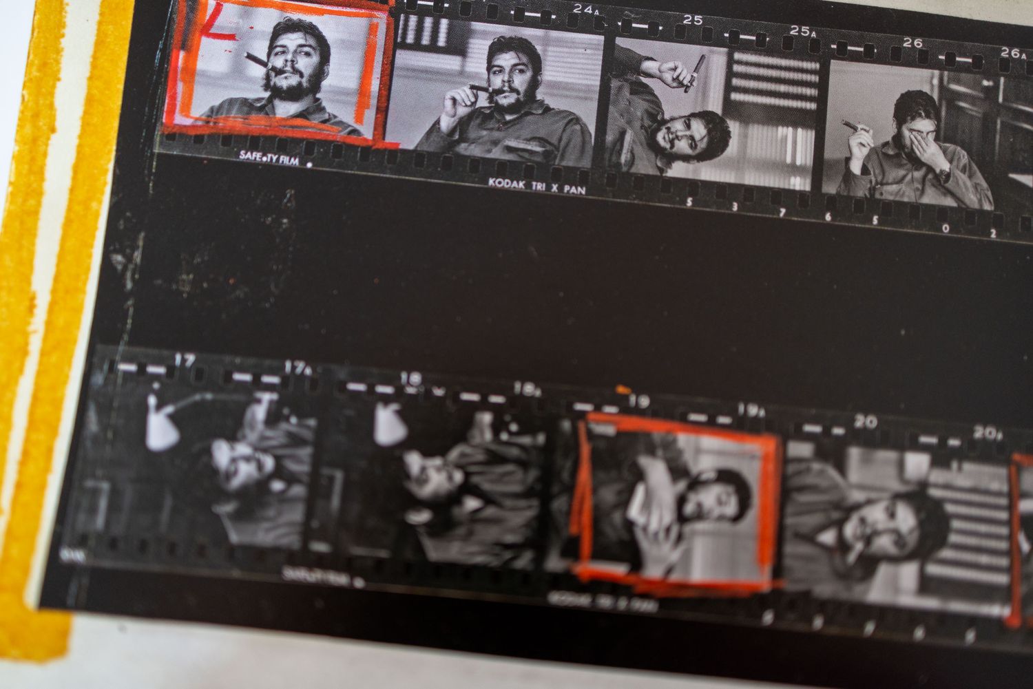 Vintage contact sheet showing black and white film negatives with one color-highlighted frame of a man smoking.