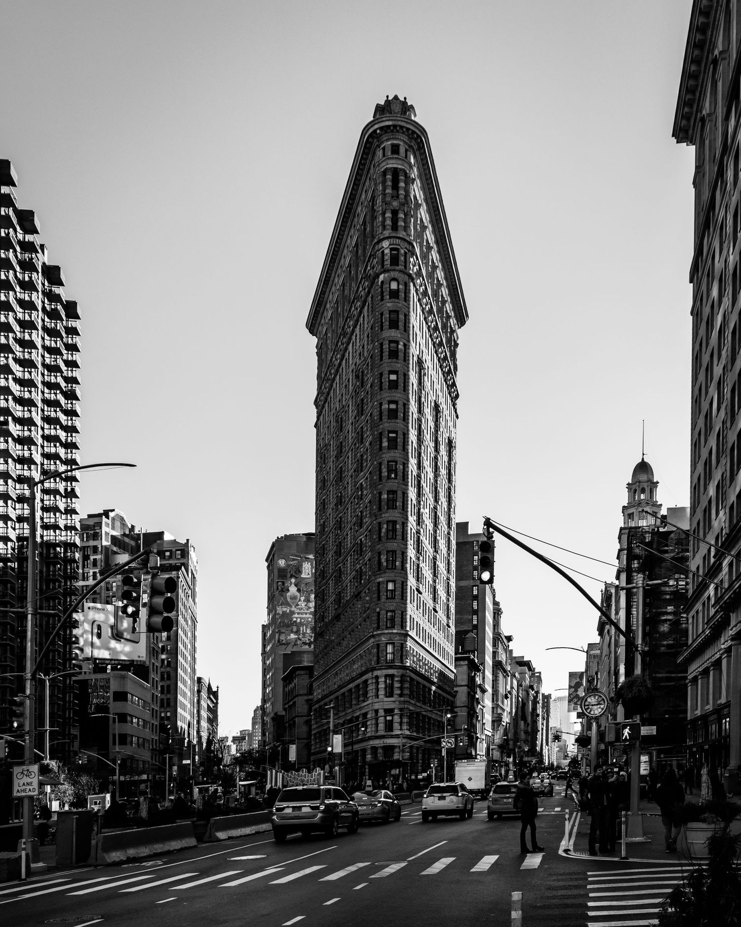 Black and white photo of the iconic Flatiron Building in New York City, framed by urban streets and surrounding skyscrapers.