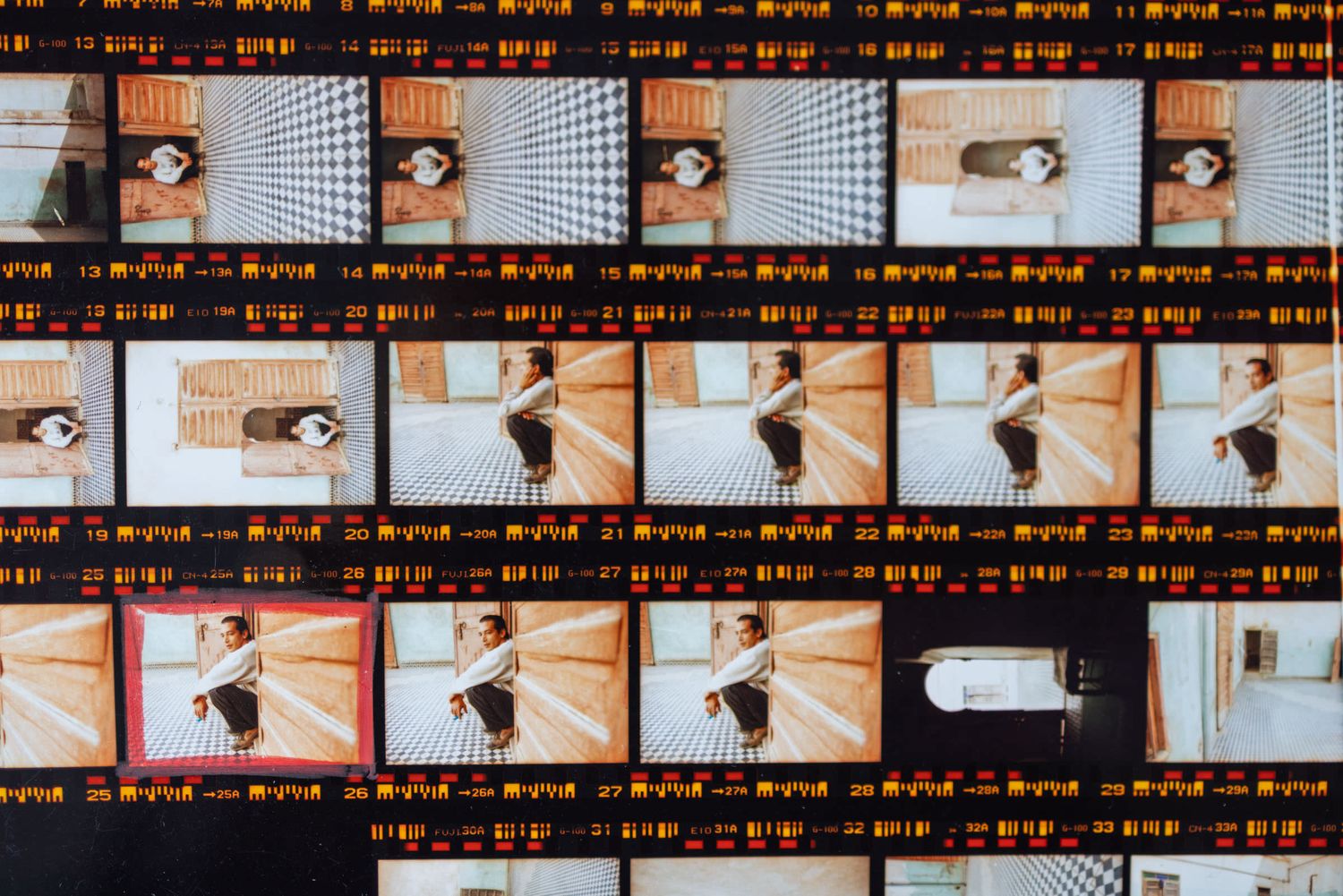A contact sheet of film photography negatives showing aerial views of a person in a room, with orange film borders.