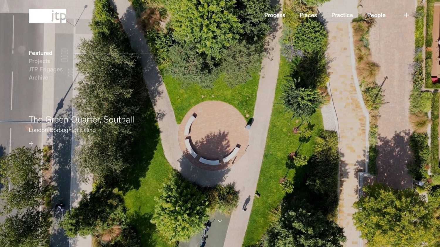 Aerial drone view of a circular gazebo surrounded by lush green trees and winding pathways in a park.