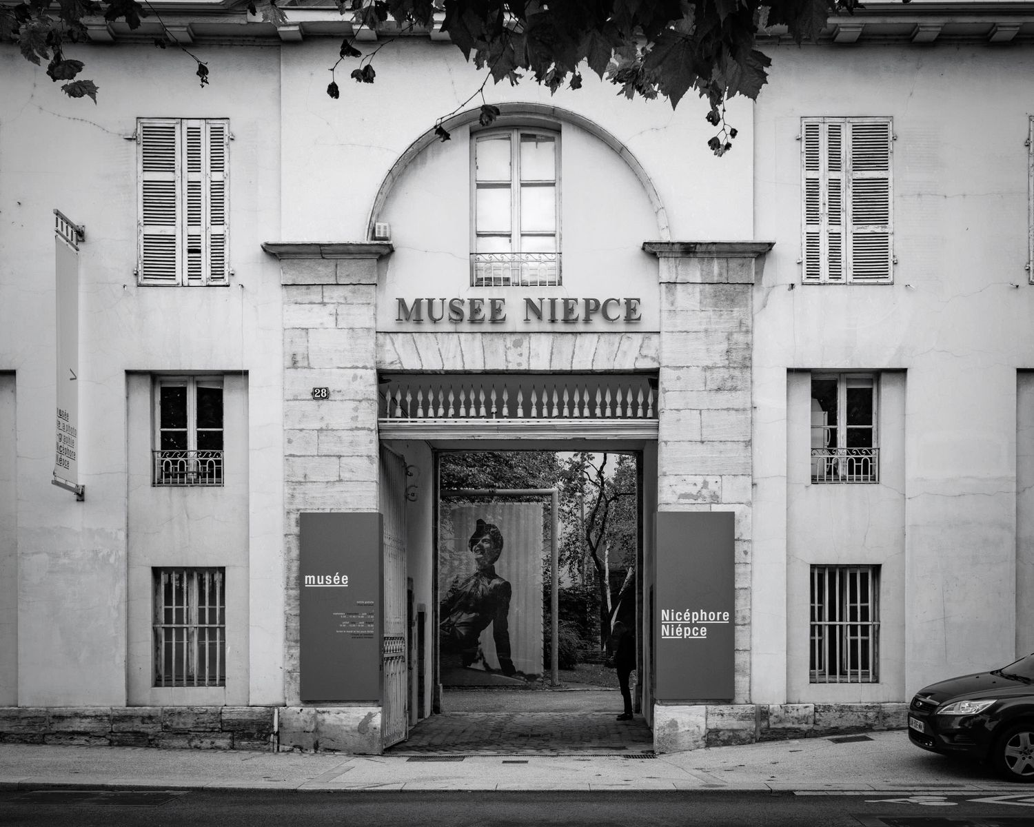 Black and white photo of the Musee Niepce museum entrance with large doors and signage in France.
