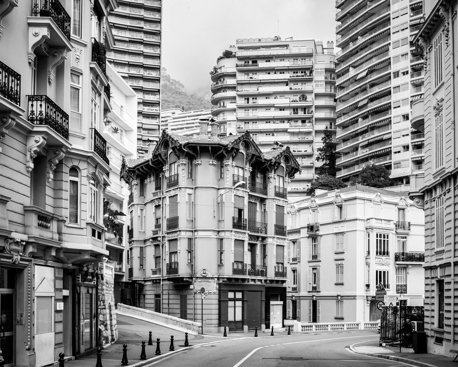 Black and white street photography of elegant Haussmann-style buildings on an empty Monaco street corner.