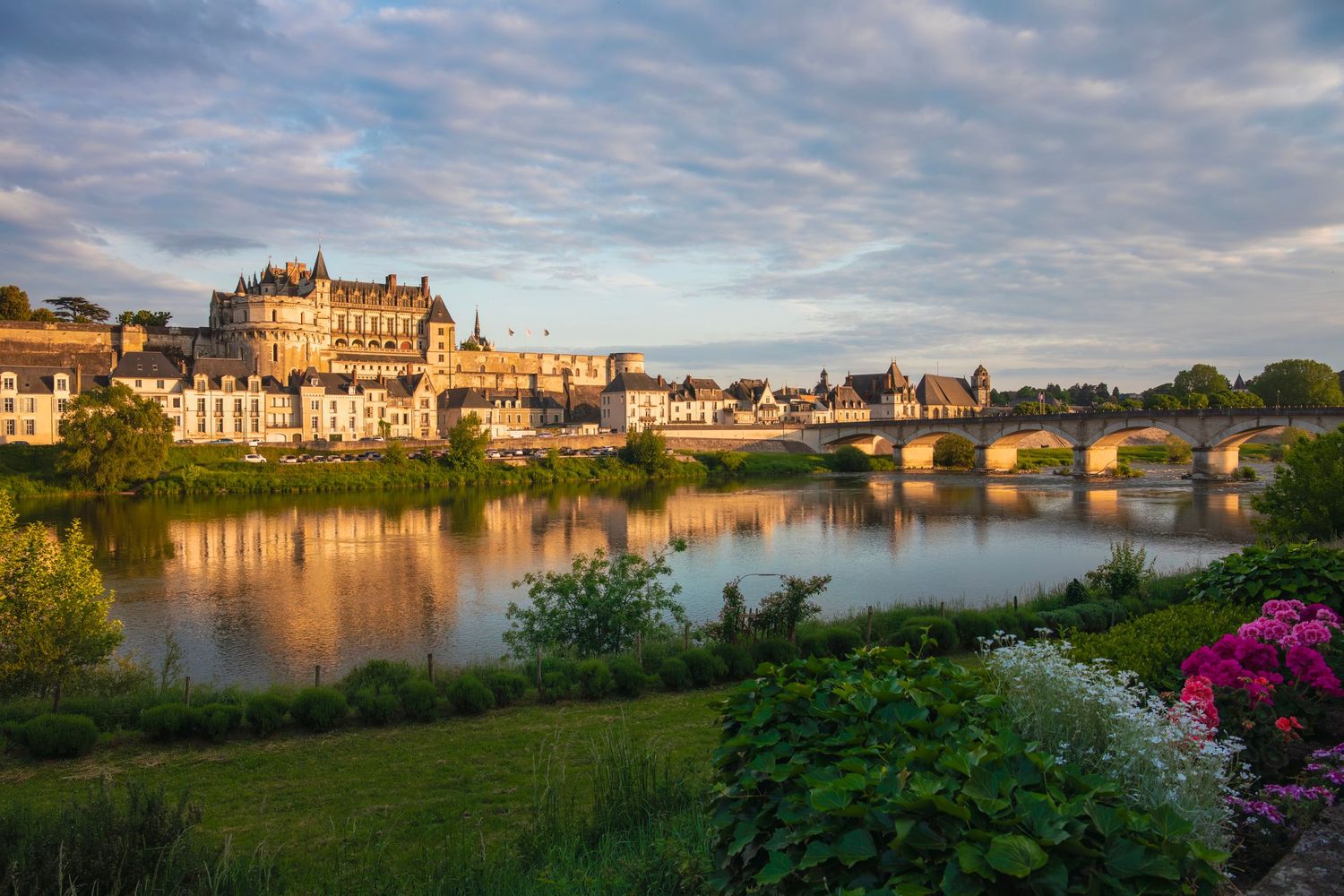Golden sunset light reflects on the Loire River with the Chateau d Amboise and bridge in France.