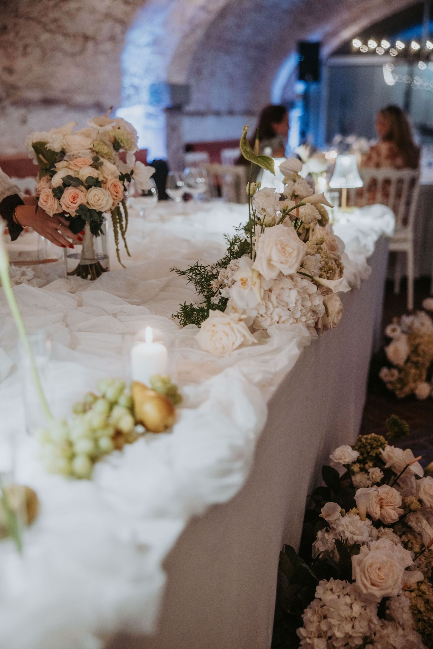 Romantic wedding reception table adorned with blush roses, hydrangeas, and candlelight decor.