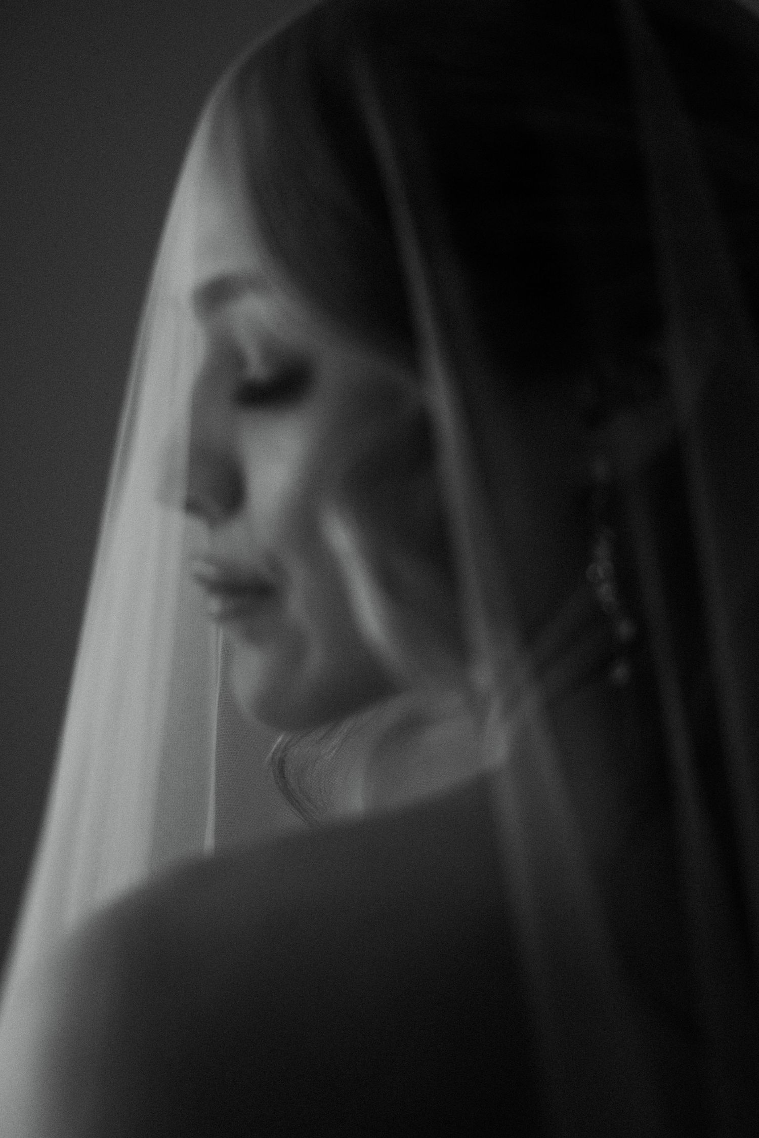 Black and white bridal portrait of a bride wearing a veil, captured in soft focus with elegant lighting.