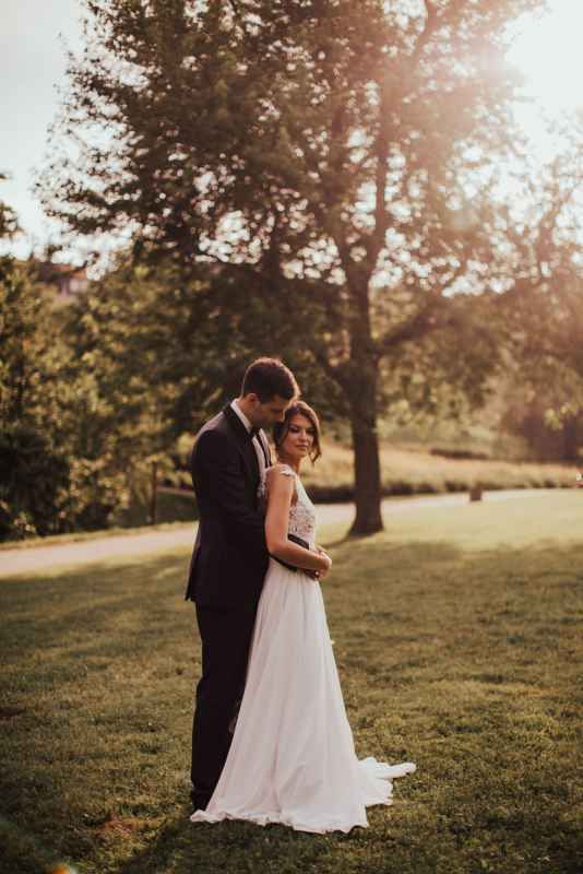 Bride and groom sharing a tender embrace in a sunlit garden park on wedding day.