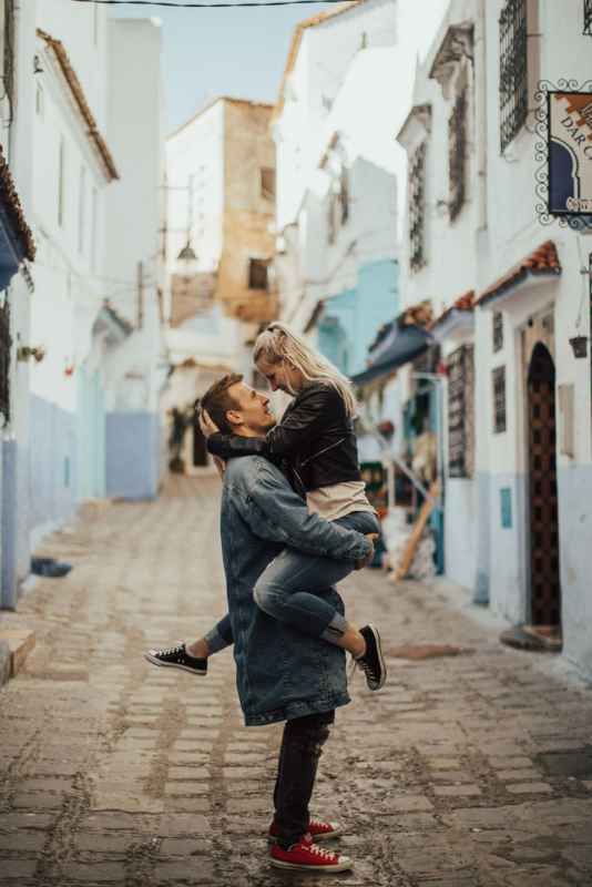 Couple sharing a romantic kiss on a cobblestone street in Chefchaouen, Morocco's blue city.
