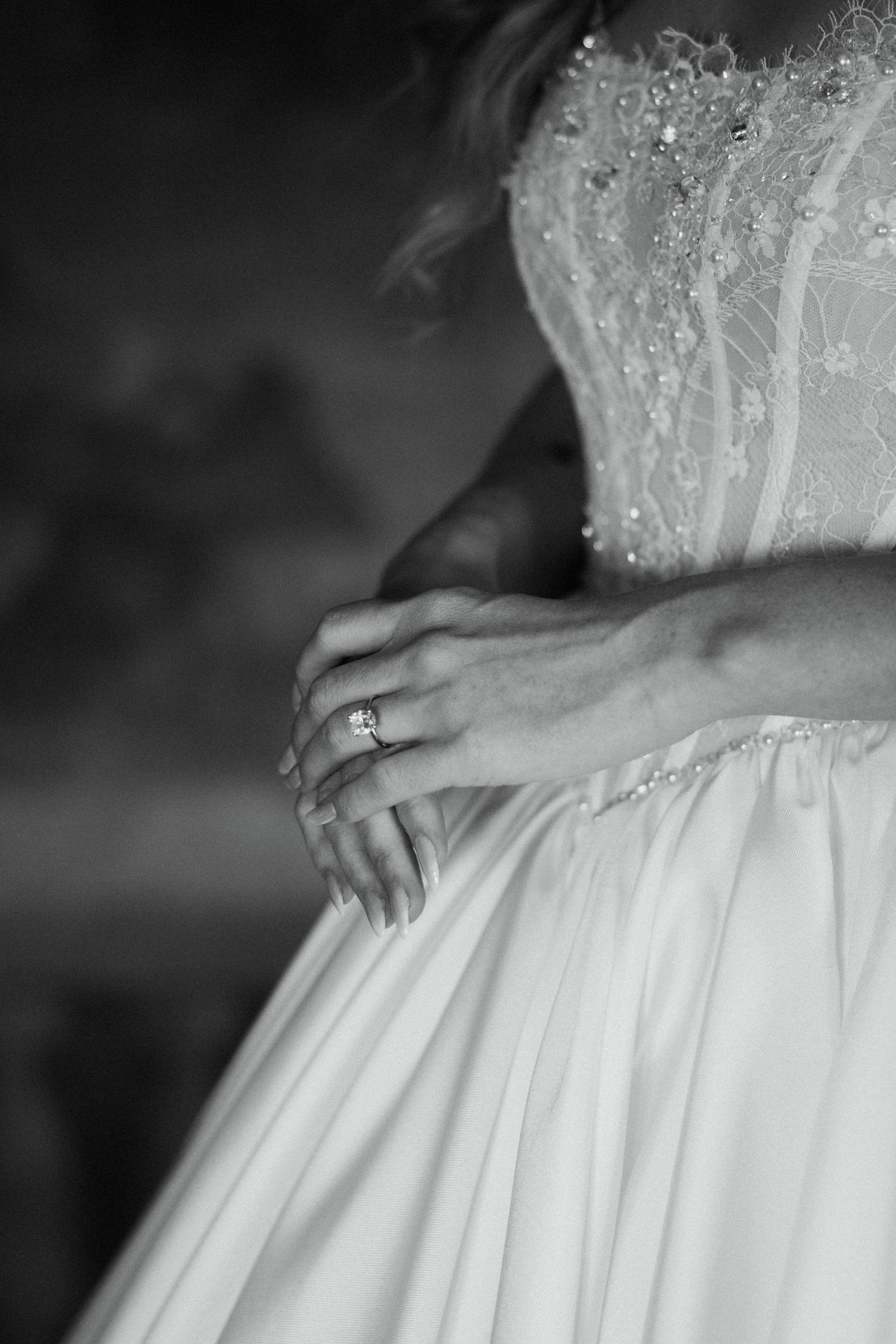 Black and white close-up of bride in lace corset wedding gown showcasing her diamond engagement ring.