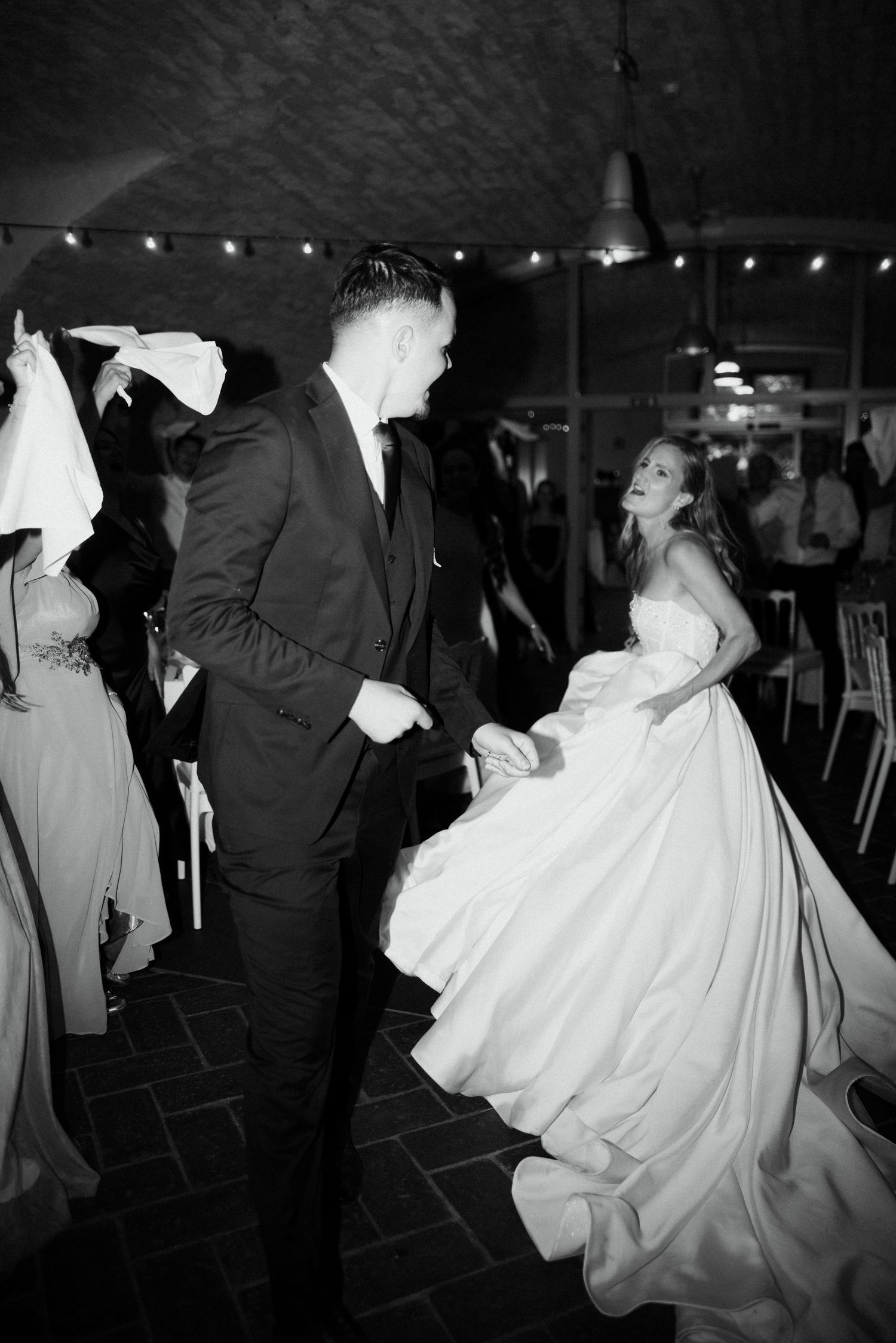 Bride and groom share a joyful dance together at their wedding reception in black and white photo.