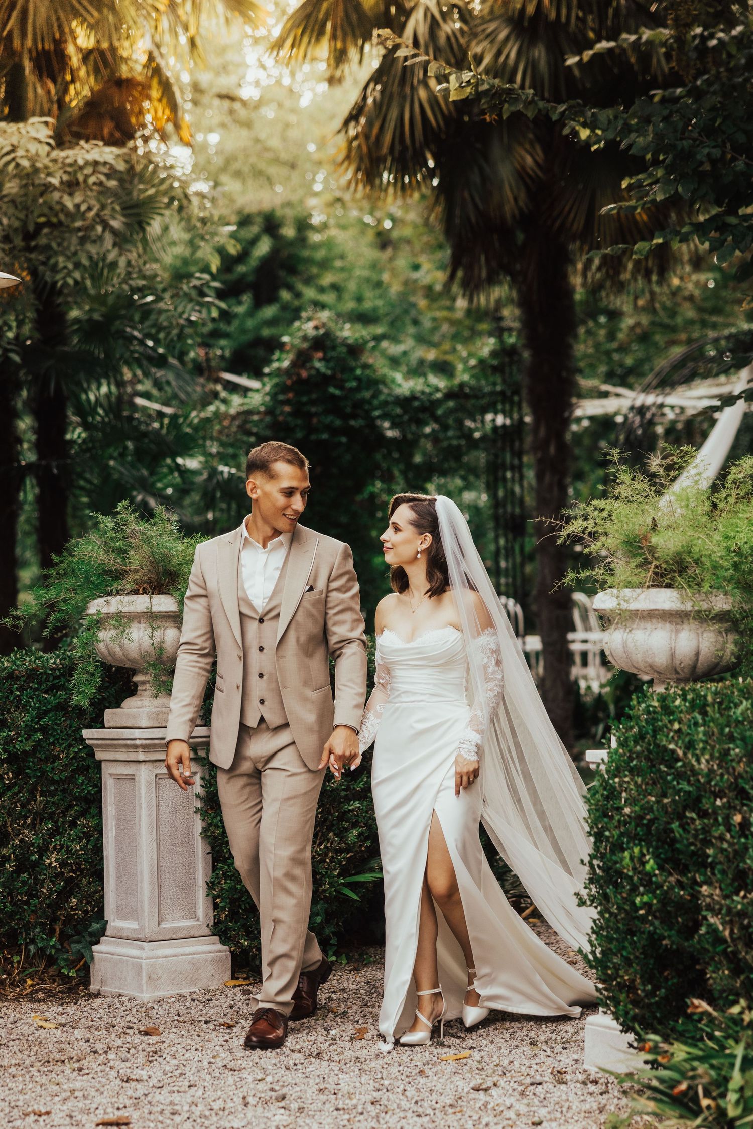 Bride and groom walking hand in hand through lush garden wedding venue.