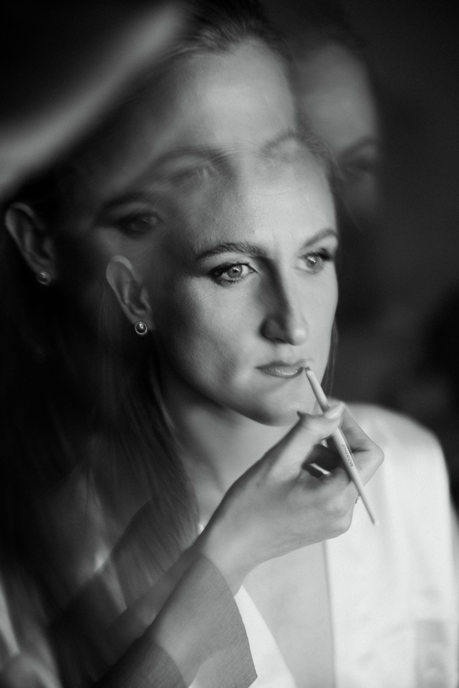 Black and white portrait of a bride having her makeup applied before the wedding.