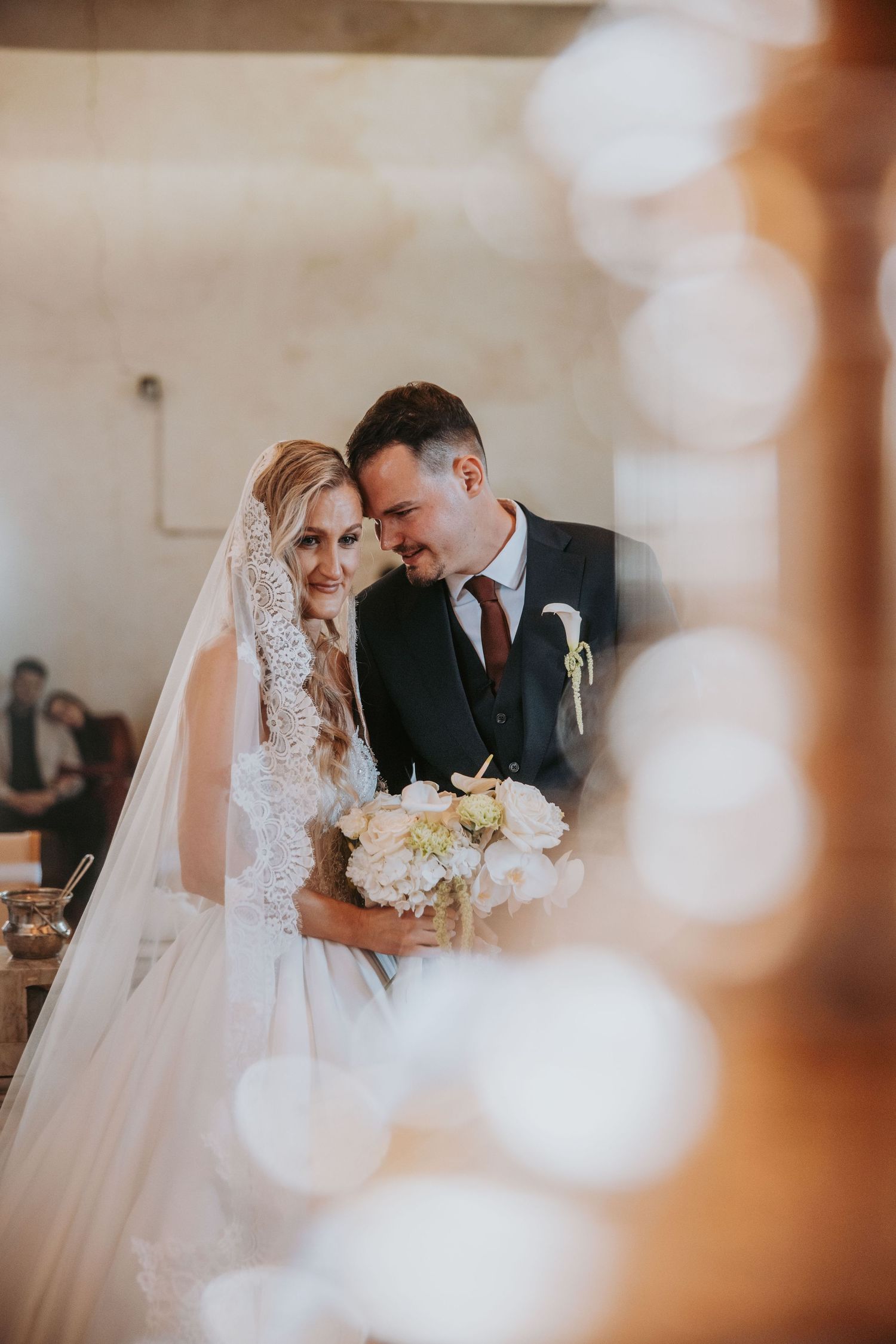 Bride and groom share an intimate moment at the altar, smiling together as she holds a white floral bouquet.