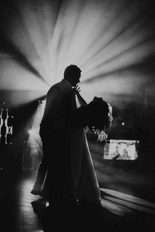 Couple sharing first dance in dramatic black and white wedding photo.