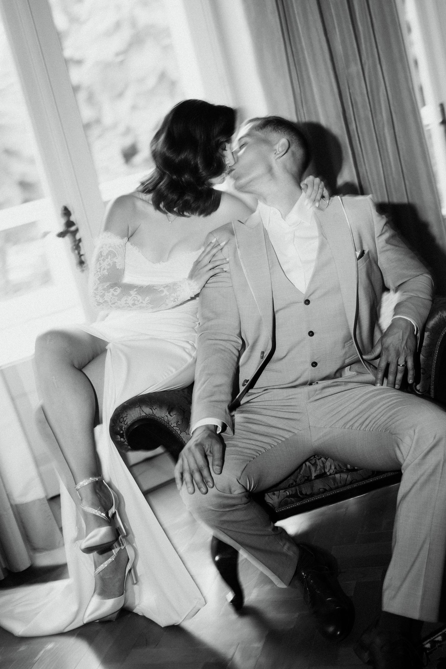 Black and white photo of bride and groom sharing intimate kiss indoors.