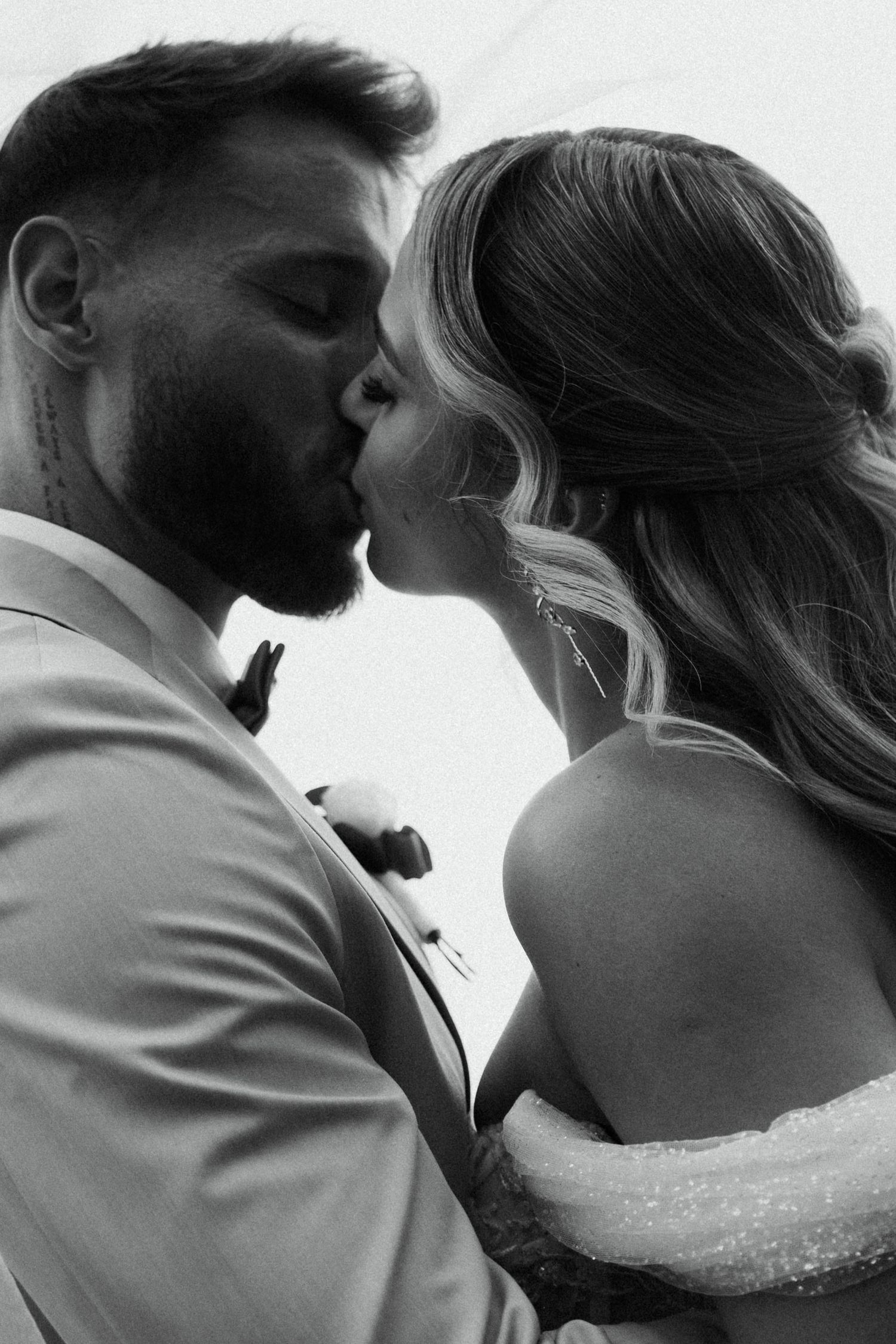 Black and white photo of bride and groom sharing first kiss at their wedding ceremony.