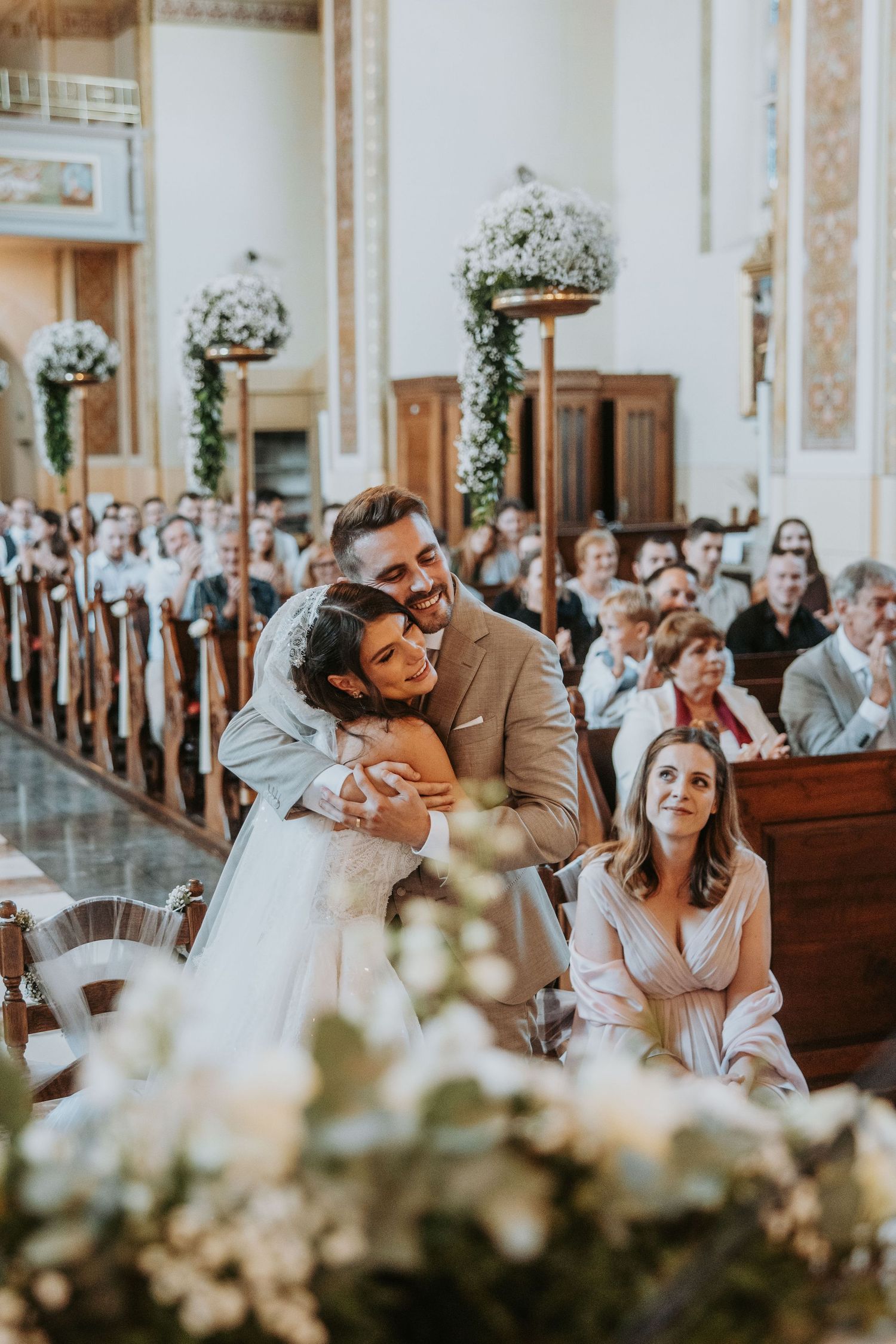 A bride and groom share a joyful hug at the altar during their church wedding ceremony.