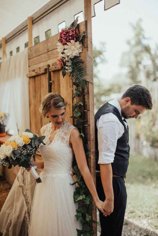 Bride and groom sharing a quiet moment of prayer at a rustic wooden altar.