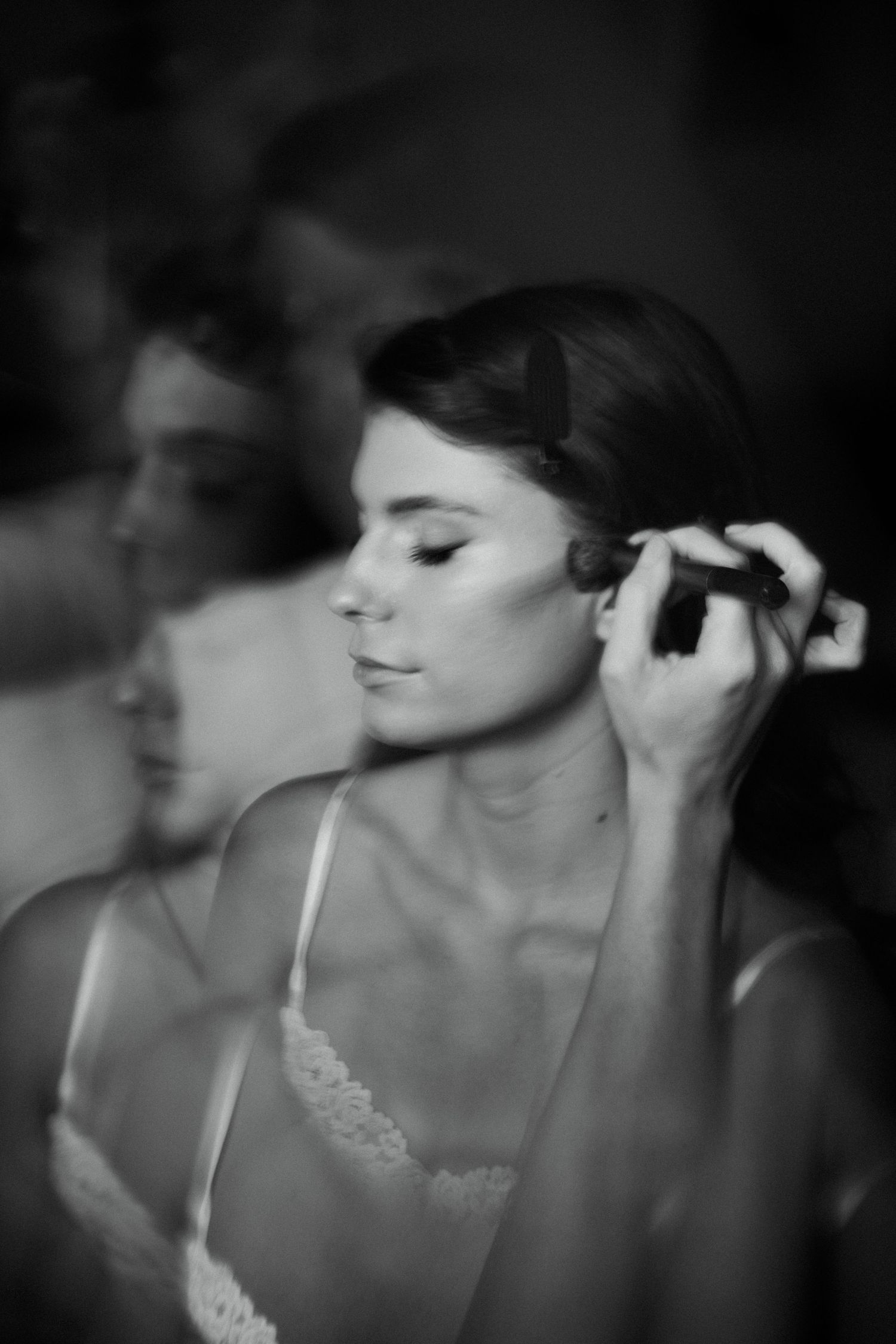 Black and white photo of a bride having her hair styled before her wedding ceremony.