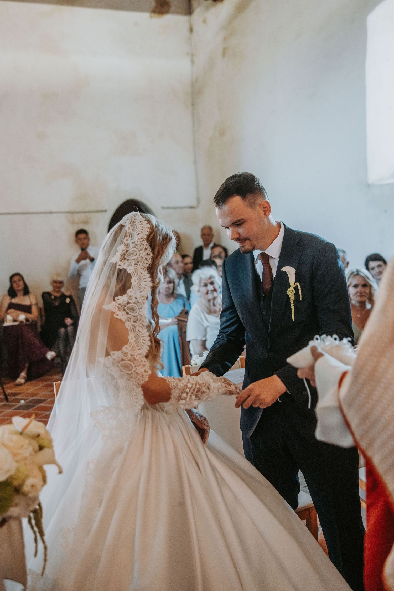 Bride and groom exchange rings at church altar during elegant wedding ceremony with guests seated in background.