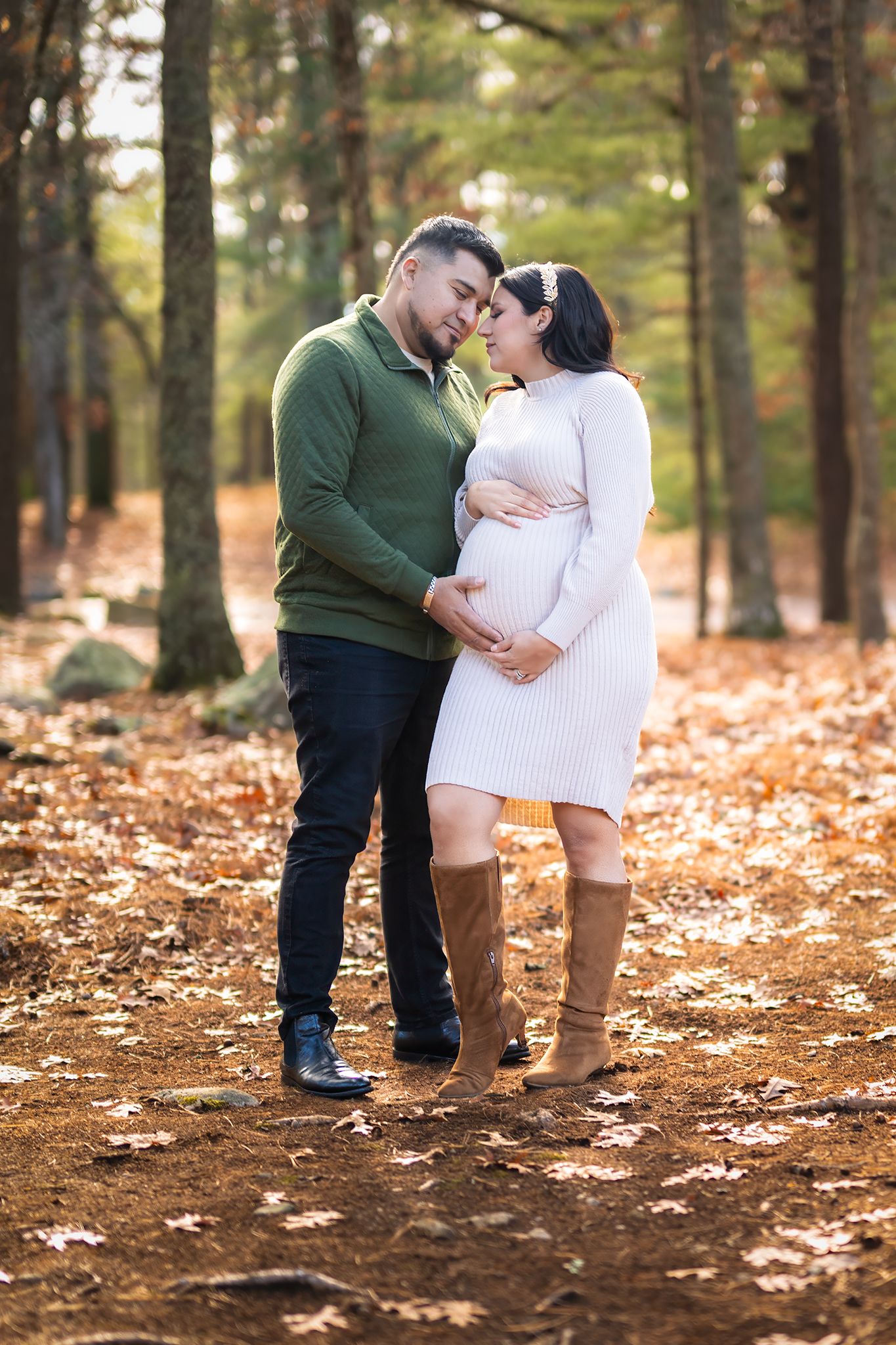 Couple sharing tender moment in autumn forest, woman in white maternity dress with baby bump.