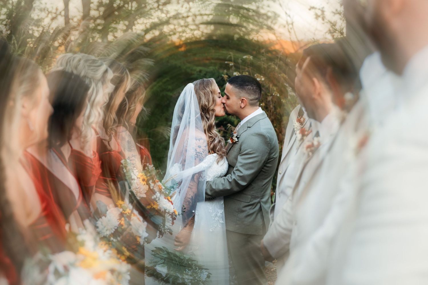 Bride and groom sharing a kiss at the altar surrounded by wedding party in a dreamy bokeh effect photo.