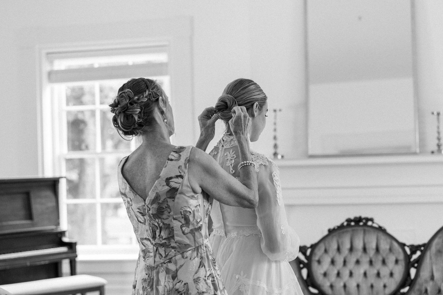 a black and white photo of a mom fixing her daughters hair before getting married.