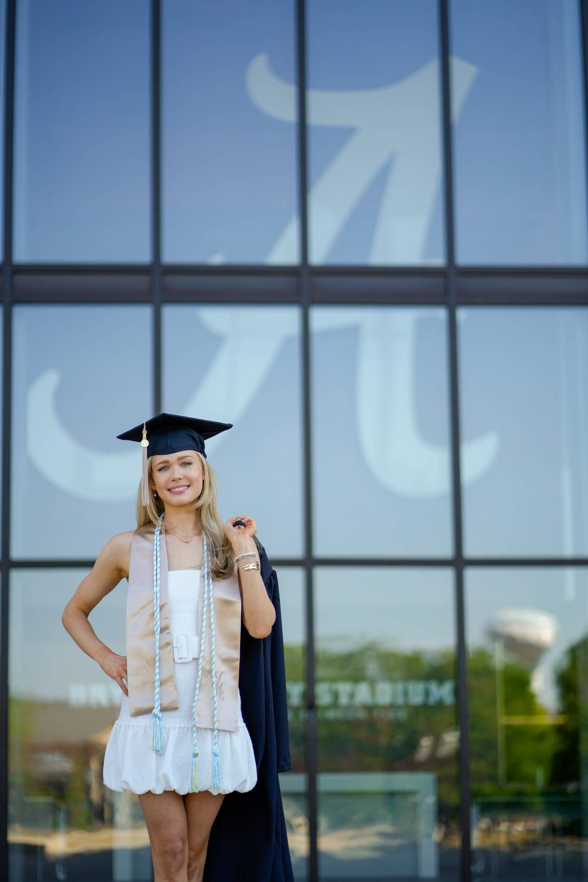 a college senior holding her gown and wearing her cap during her grad photo session.