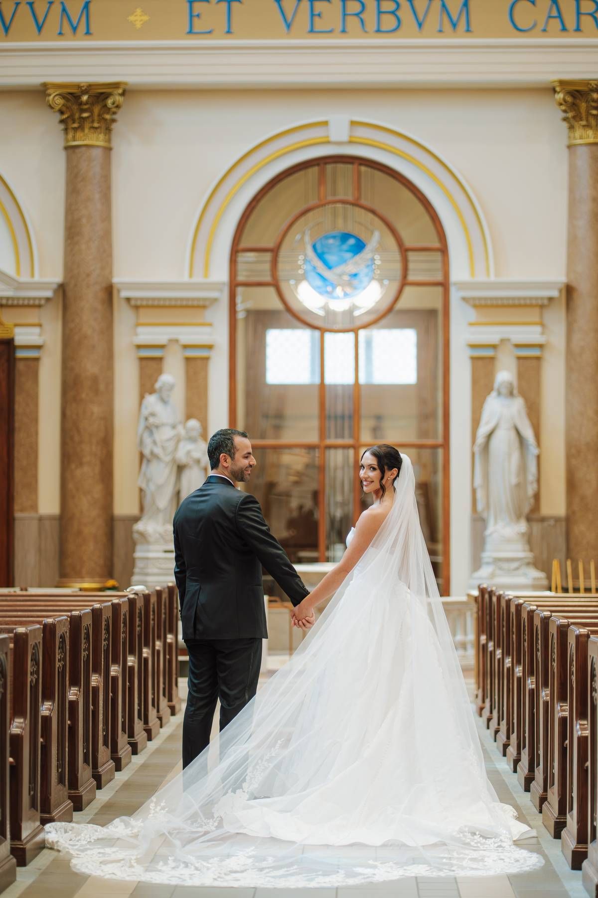 a newlywed couple holding hands in a cathedral after getting married.