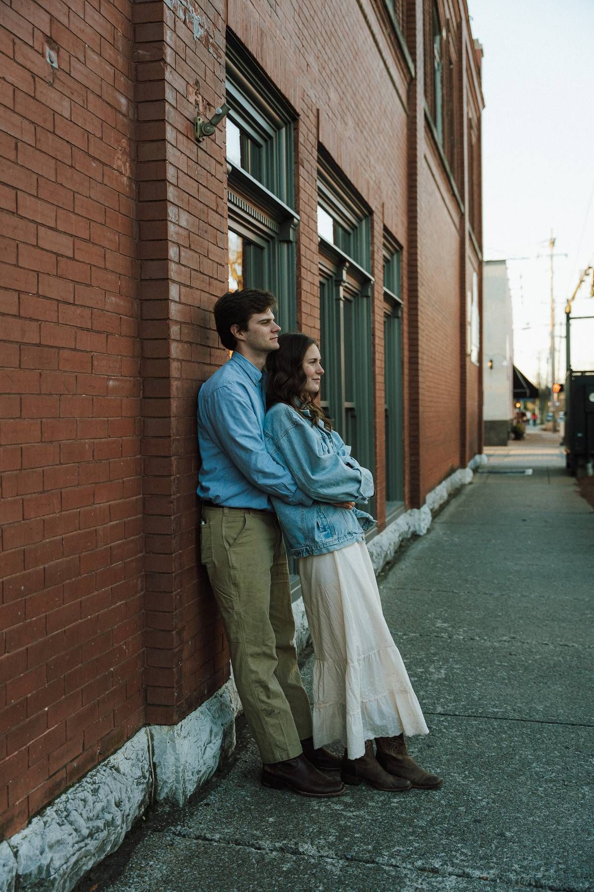 a couple leaning against a brick city wall