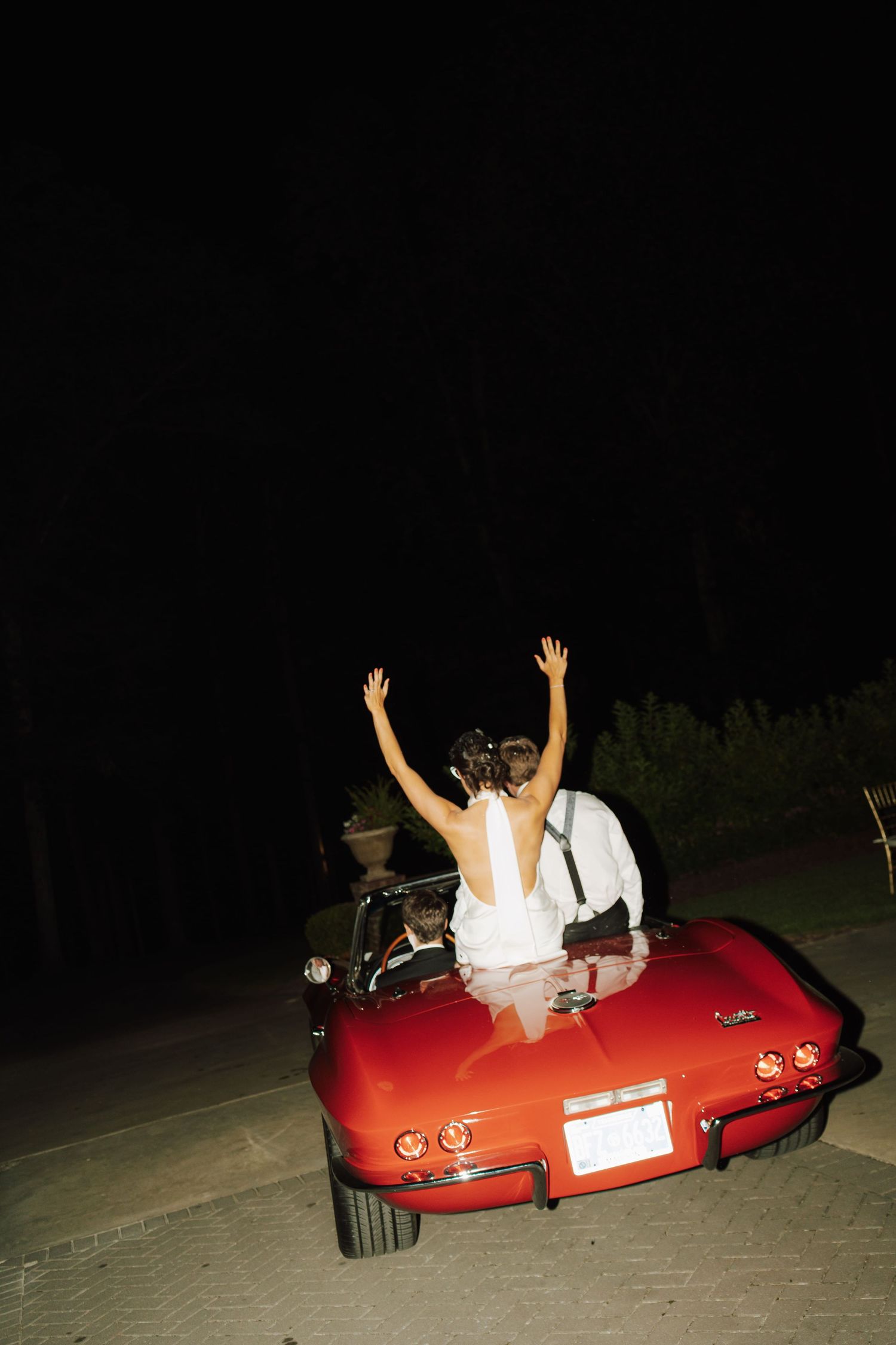 a newlywed couple driving off in a car after their reception