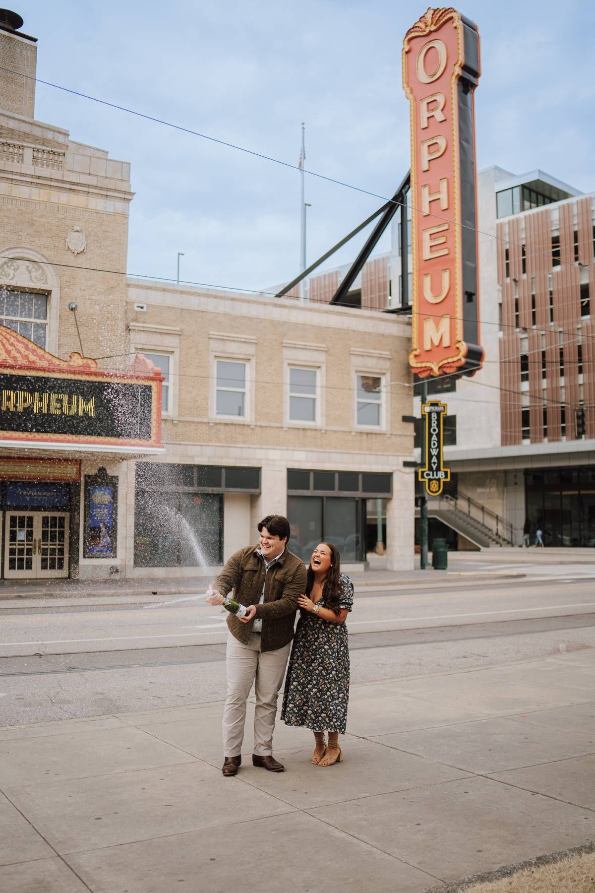 A newly engaged couple standing in the city of Memphis, spraying champgne together celebrating.