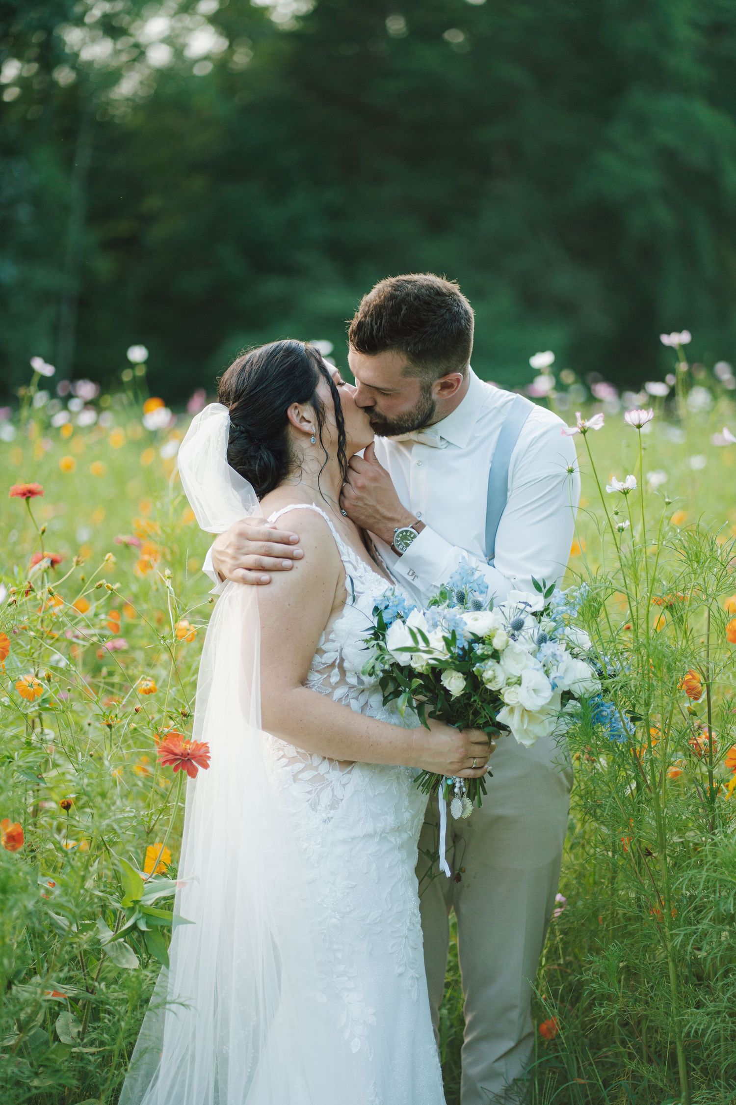 a newlywed couple kissing in a field of flowers