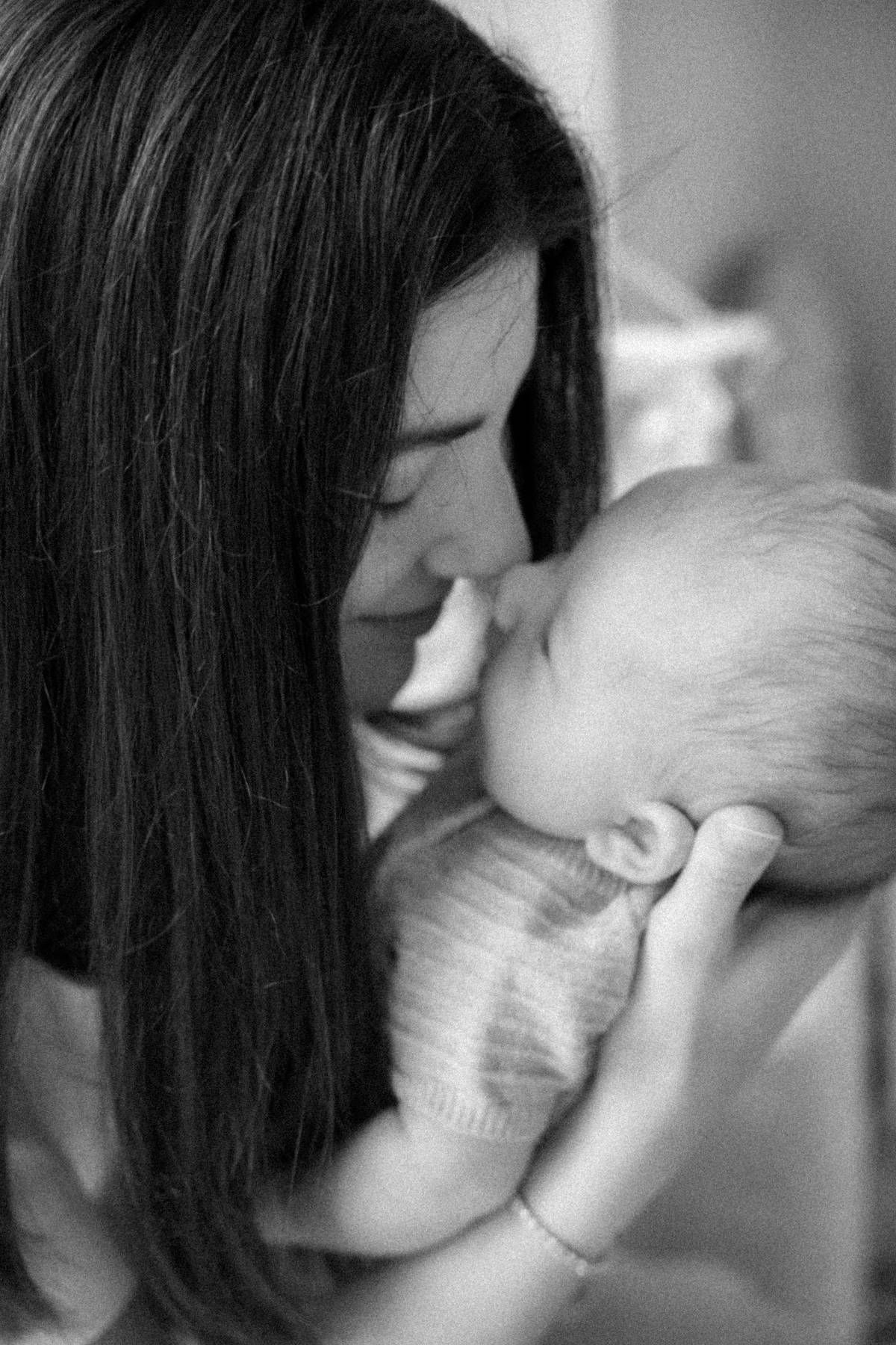 a mom kissing her newborn baby