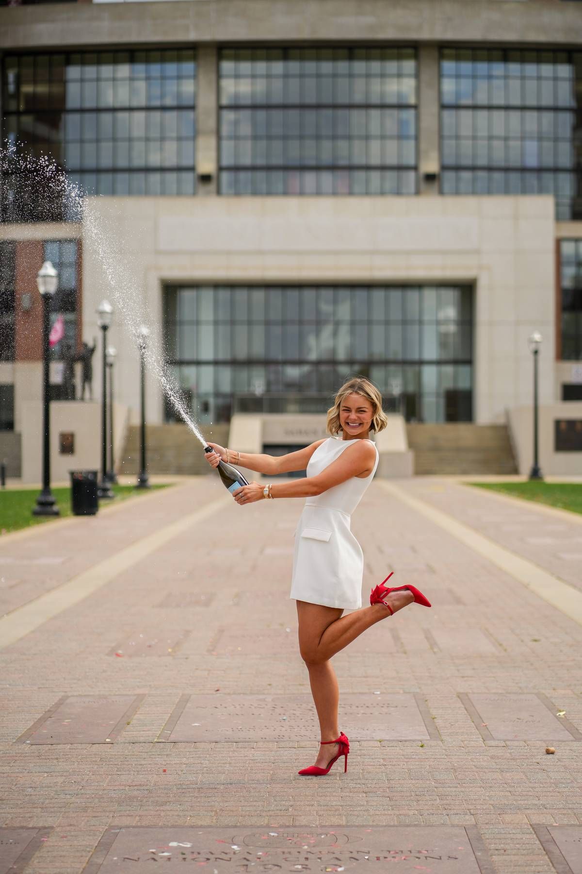 a college senior praying champagne during her senior photo session.