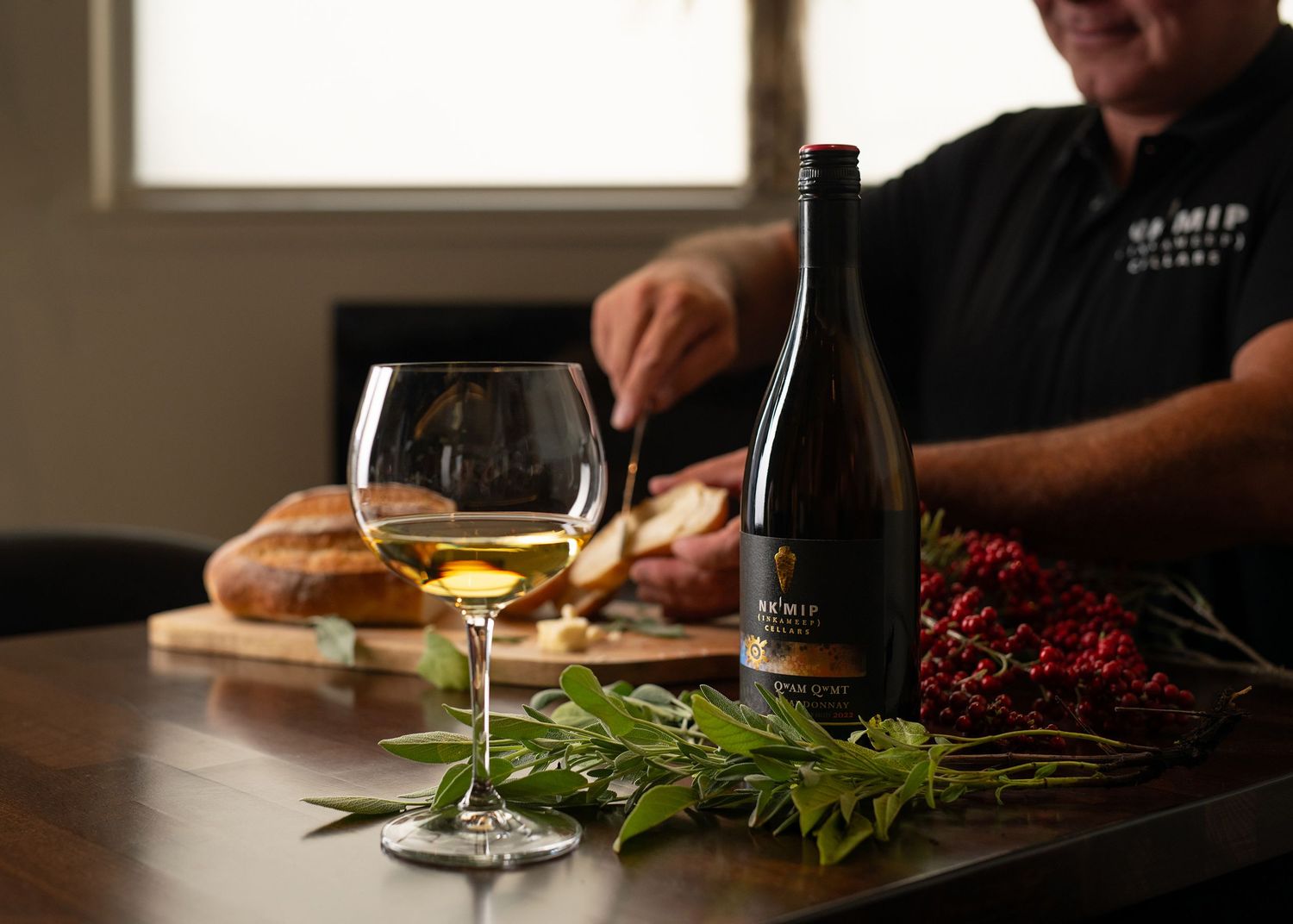 Man pouring wine beside a glass of white wine, charcuterie board, and holiday decor at S'MIP Cellars winery.