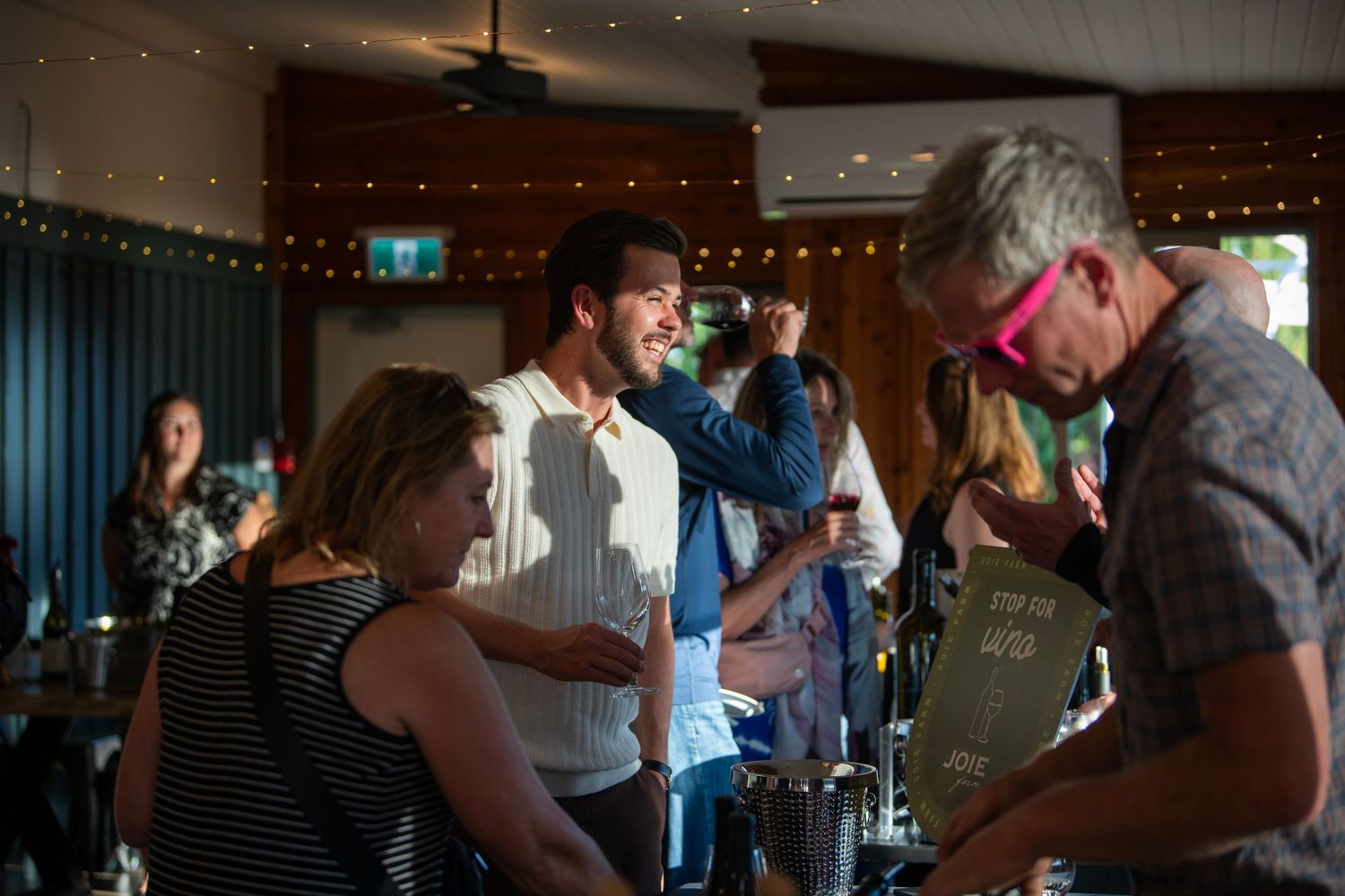 People socializing at a lively indoor bar event with string lights and drinks.